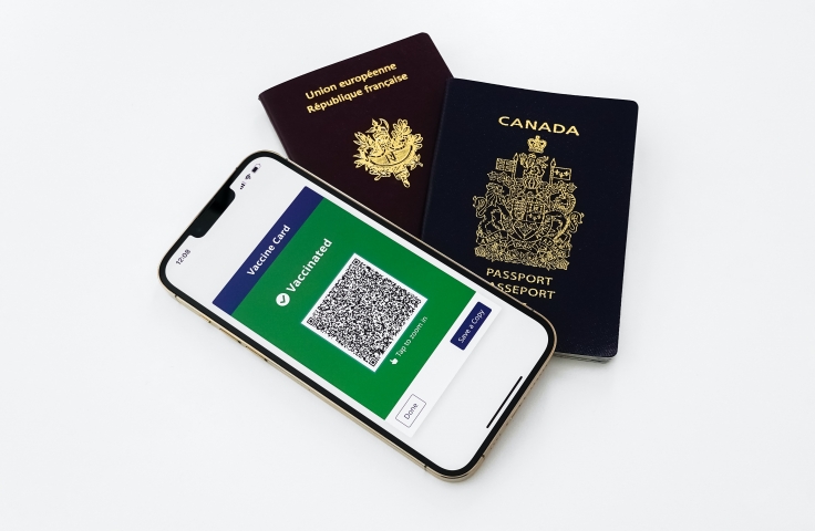 A phone with a vaccine certificate is on top of a European passport and a Canadian passport